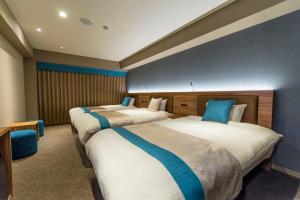 a hotel room with three beds with blue pillows at Wat Hotel & Spa Hida Takayama in Takayama