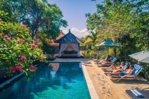 a group of people sitting in chairs next to a swimming pool at Minabali Bunga'lo in Tulamben