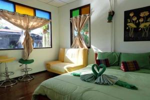 a bedroom with a green bed and a couch at Baan Ing Suan in Amphawa