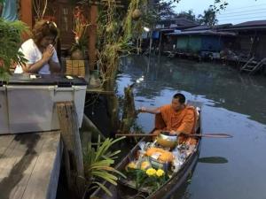 a man sitting in a boat on the water at Baan Ing Suan in Amphawa