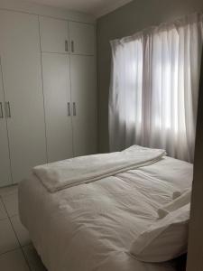 Una cama blanca en una habitación con ventana. en Tuna Self Catering, en Swakopmund