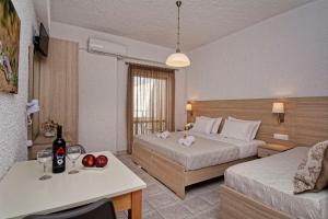 a hotel room with two beds and a table with wine glasses at Studios George in Palaiochora