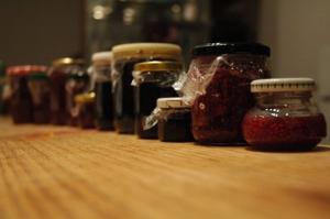 a row of jars of jam on a wooden table at Le Manoir de Presle - Chambres d'Hôte in Montaigu-le-Blin