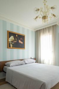 una camera da letto con un grande letto bianco e un lampadario a braccio di Little House a Campo San Martino