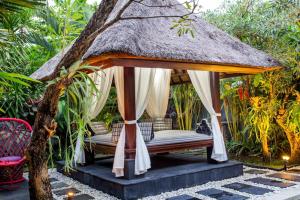 een prieel met een bed in een tuin bij Tiga Samudra Villa in Canggu