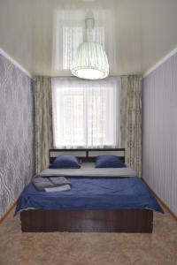 a bedroom with a bed with blue sheets and a window at 2 комнатные апартаменты на Габдуллина 46а in Kokshetau