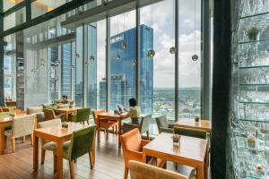 a restaurant with tables and chairs and large windows at Oasia Hotel Novena, Singapore by Far East Hospitality in Singapore