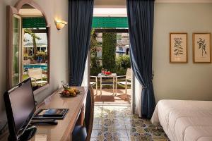 a bedroom with a bed and a desk with a television at Hotel Continental Ischia in Ischia