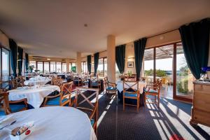 a restaurant with white tables and chairs and windows at Hotel La Baia in Bari