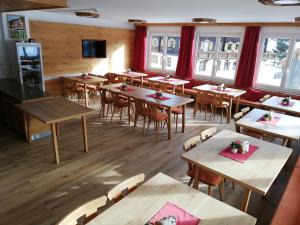 ein leeres Restaurant mit Tischen, Stühlen und Fenstern in der Unterkunft Wurlerhof in Kals am Großglockner