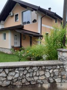 una casa con una pared de piedra delante de ella en Sweet Holiday Home, en Hadžići