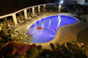 a swimming pool at night with a red umbrella at Castle Konti in Tirana