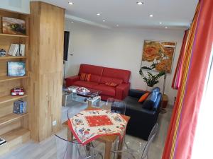 ロウファッハにあるGite duplex du vignoble Alsaceのリビングルーム(赤いソファ、テーブル付)