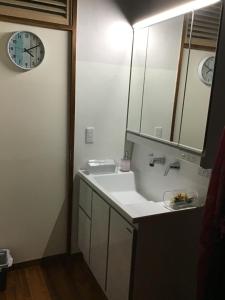 ein Badezimmer mit einem Waschbecken und einer Uhr an der Wand in der Unterkunft Kami House in Amami
