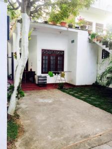 a white house with a tree in front of it at City Bay House in Weligama