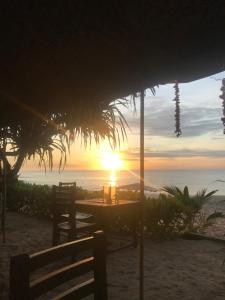 um pôr do sol na praia com um banco na praia em Mallika Guest House em Tangalle
