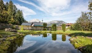 a pond in front of a house with mountains in the background at Haus Christl am Horn in Sankt Johann in Tirol