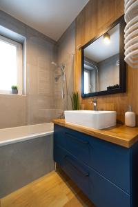 a bathroom with a sink and a mirror and a tub at Apartamenty Lisowski CENTRUM Goszczyńskiego in Zakopane