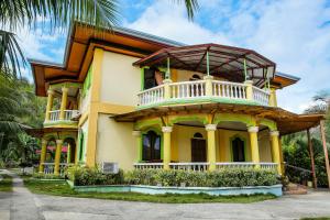 a yellow house with a balcony on top of it at OYO 422 Villa Emilia Pension House in Panglao
