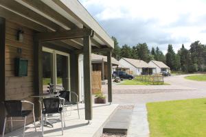 a porch of a house with chairs and a table at 2 Dellmhor Cottages in Aviemore