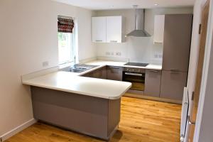 a kitchen with white cabinets and a white counter top at 2 Dellmhor Cottages in Aviemore