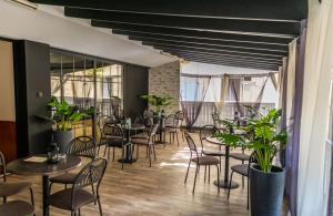 テッサロニキにあるヴェルギナ ホテルのテーブルと椅子、植物のあるレストラン