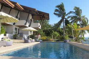 奧斯洛布的住宿－Emoha Dive Resort，一座带遮阳伞的房屋前的游泳池
