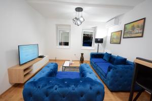 ein Wohnzimmer mit blauen Sofas und einem TV in der Unterkunft Cvetkovic LUX Аpartmani & Free GARAŽA in Vrnjačka Banja