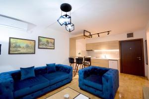 a living room with a blue couch and a kitchen at Cvetkovic LUX Аpartmani & Free GARAŽA in Vrnjačka Banja