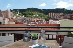 Bilbao City Center by abba Suites في بلباو: طاولة مع كأسين من النبيذ على شرفة