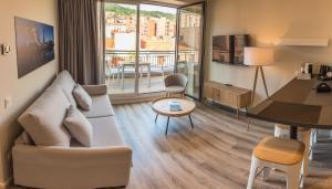 Bilbao City Center by abba Suites في بلباو: غرفة معيشة مع أريكة وطاولة