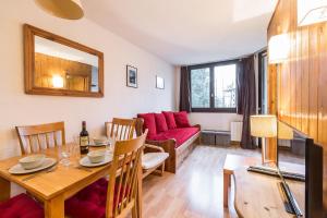 uma sala de estar com uma mesa e um sofá vermelho em Apartment Chamois Blanc 2B em Chamonix-Mont-Blanc