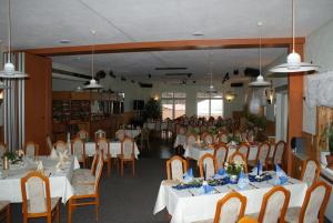 a banquet hall with white tables and chairs and people at Strandhotel Mirow in Mirow