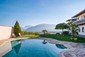 una piscina en el patio trasero de una casa con montañas al fondo en Strahlerhof, en Appiano sulla Strada del Vino