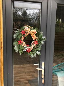 une couronne de christmas sur la porte d'entrée d'une maison dans l'établissement Le domaine des hauts de canche Magnifique Tiny house avec Spa, à Étaples