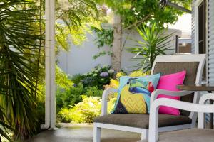 a white chair with a colorful pillow on a patio at Ocean Breeze in Huskisson