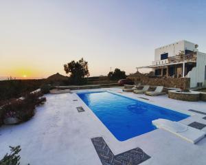 - une piscine avec des chaises et le coucher de soleil en arrière-plan dans l'établissement Villa Mozaik, à Plaka