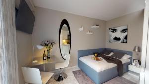 a bedroom with a bed with a desk and a mirror at VISIONAPARTMENTS Rotachstrasse - contactless check-in in Zurich