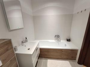 a white bathroom with a tub and a sink at Apartament Parkowy in Rzeszów