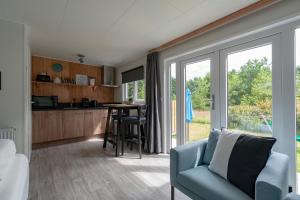 a living room with a blue couch and a kitchen at Chalet studio Mees - Texel in De Koog