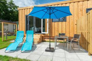a patio with a table and chairs and a blue umbrella at Chalet studio Mees - Texel in De Koog