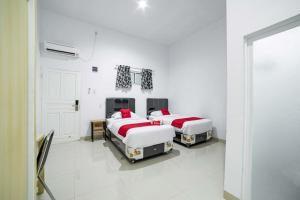 two beds in a room with white walls at RedDoorz Plus near Thamrin Plaza Medan in Medan