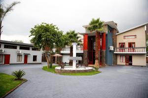 a building with a courtyard with palm trees in front of it at Travetel OR Tambo Airport in Kempton Park