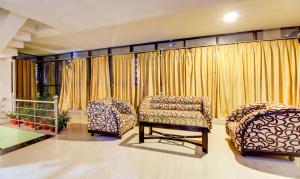two chairs and a couch in a room with curtains at Hotel Amanda in Lucknow +34 photos