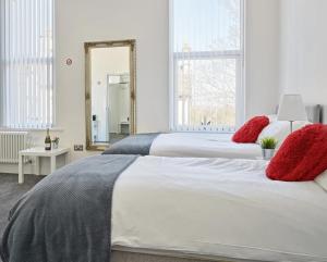 a bedroom with two beds with red pillows and a mirror at 88 Anfield Road in Liverpool