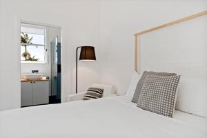 1 dormitorio blanco con 1 cama blanca y 1 silla en Studio Ocean Breeze @ Huskisson en Huskisson