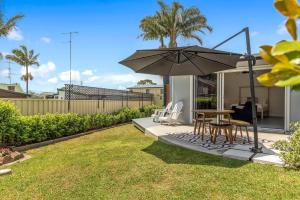 a patio with a table and chairs and an umbrella at Studio Ocean Breeze @ Huskisson in Huskisson