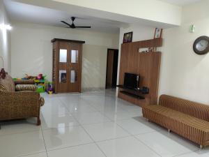 a living room with couches and a tv on the wall at Orchid Suites Apartments in Mysore