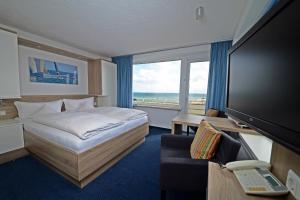 a hotel room with a bed and a large window at Hotel Quisisana & Appartements Quisi in Helgoland