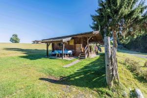 eine Blockhütte auf einem Feld mit einem Baum in der Unterkunft Almliesl HOLL-361 in Hollersbach im Pinzgau